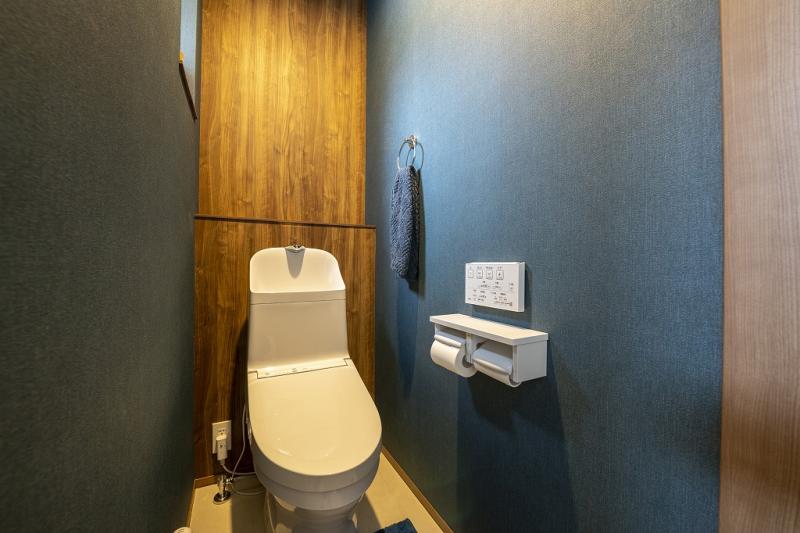 トイレ:2階のトイレは両サイドにネイビーのクロスを、正面はアクセントに木目調のクロスを採用