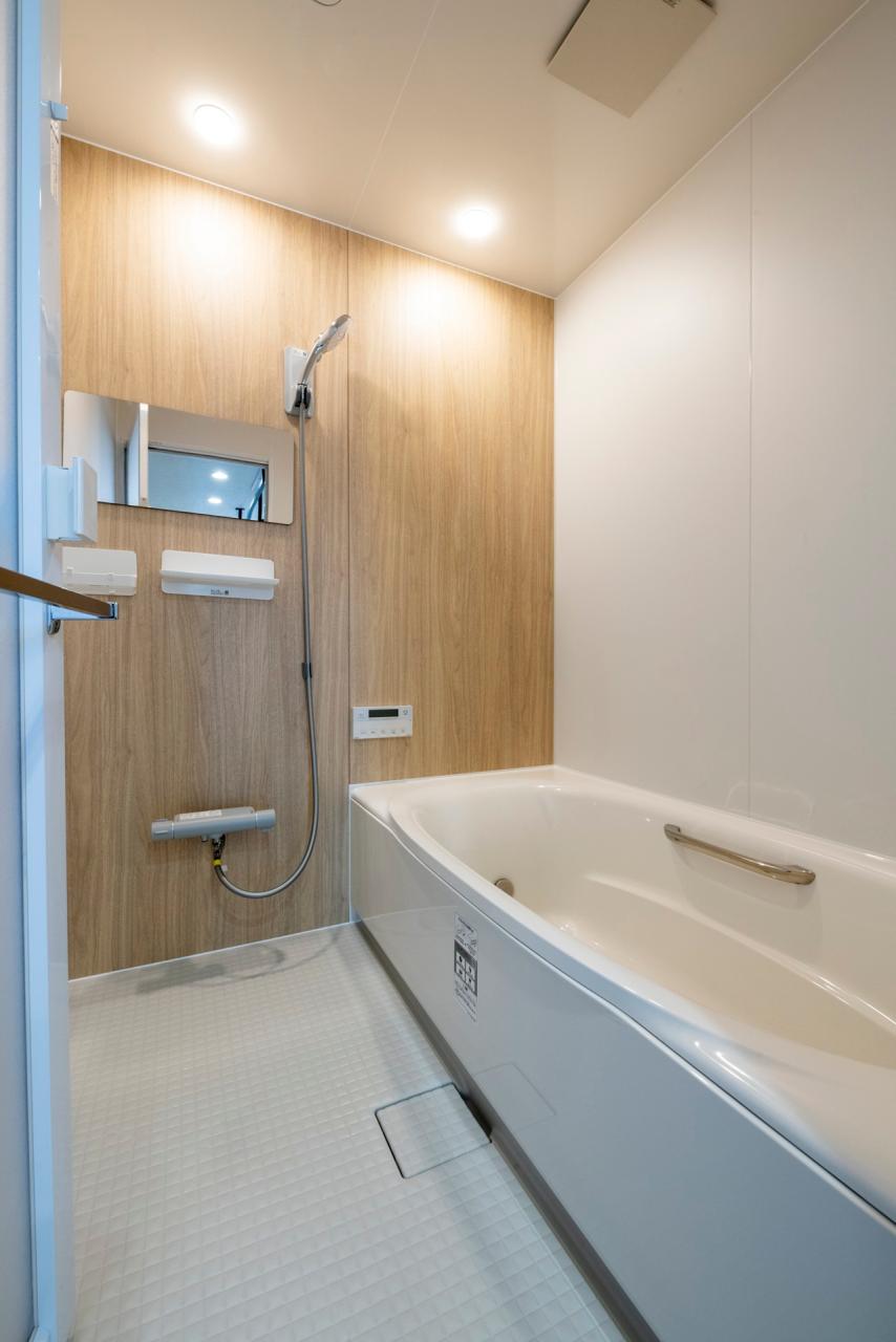 バスルーム：木目調のアクセントパネルと照明で柔らかな印象なのバスルーム