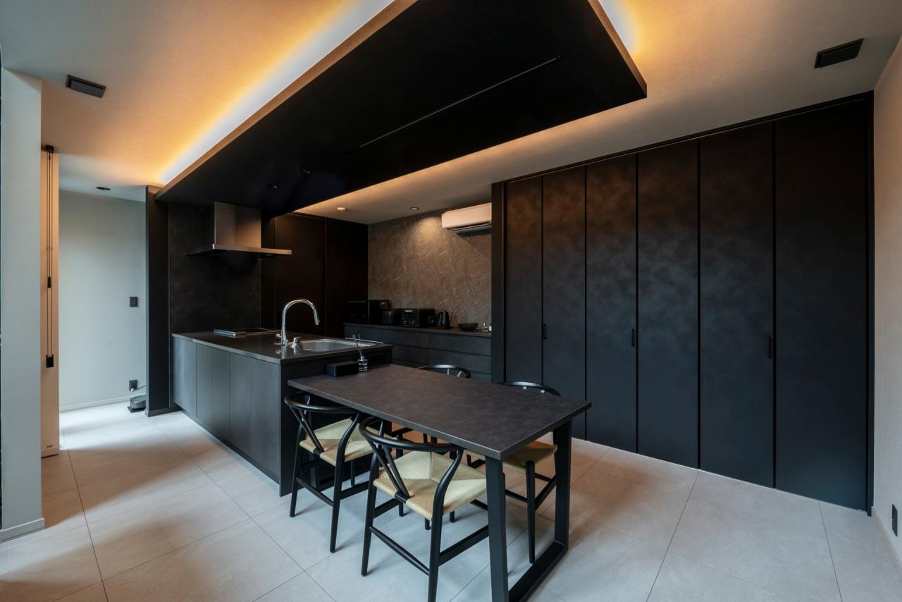 ダイニング、キッチン、照明：下がり天井と間接照明で緩やかにゾーニングされた空間