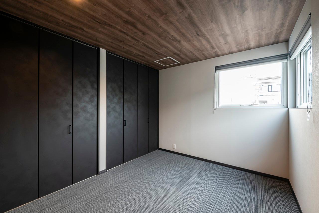 寝室：木目調クロスの天井とカーペットタイル敷きで高級感漂う主寝室