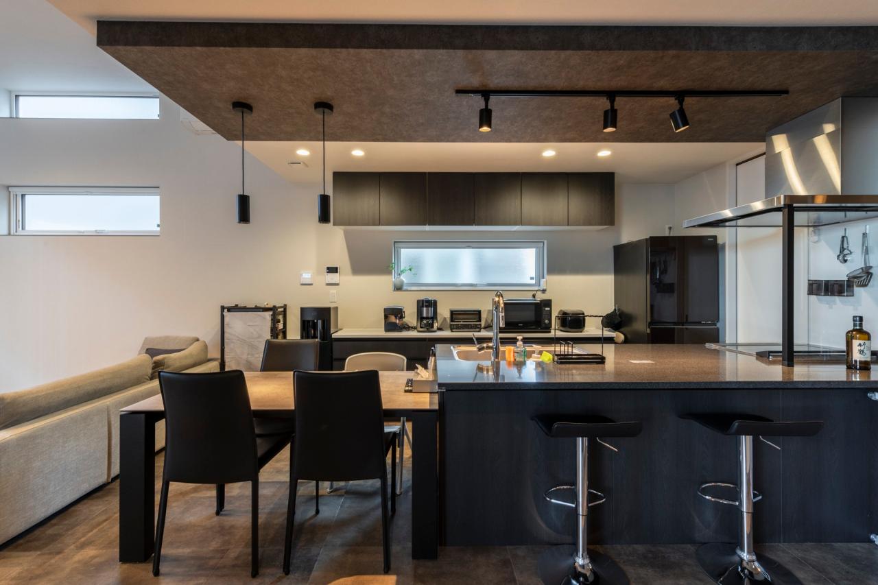 ダイニング、キッチン：ダークトーンの下がり天井とブラックにまとめられたキッチン