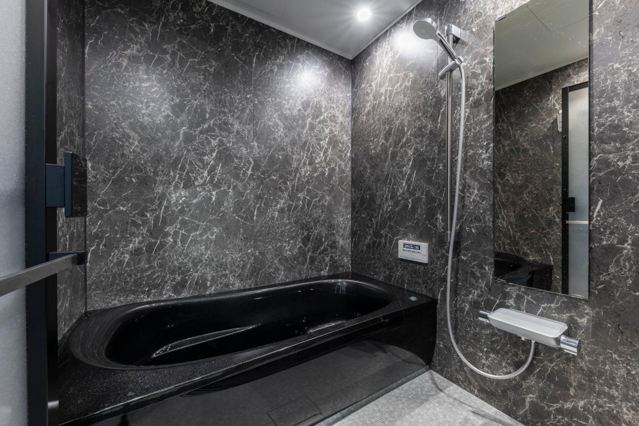 バスルーム、設備：石目調のアクセントパネルとブラックの浴槽でスパの様な高級感漂うバスルーム