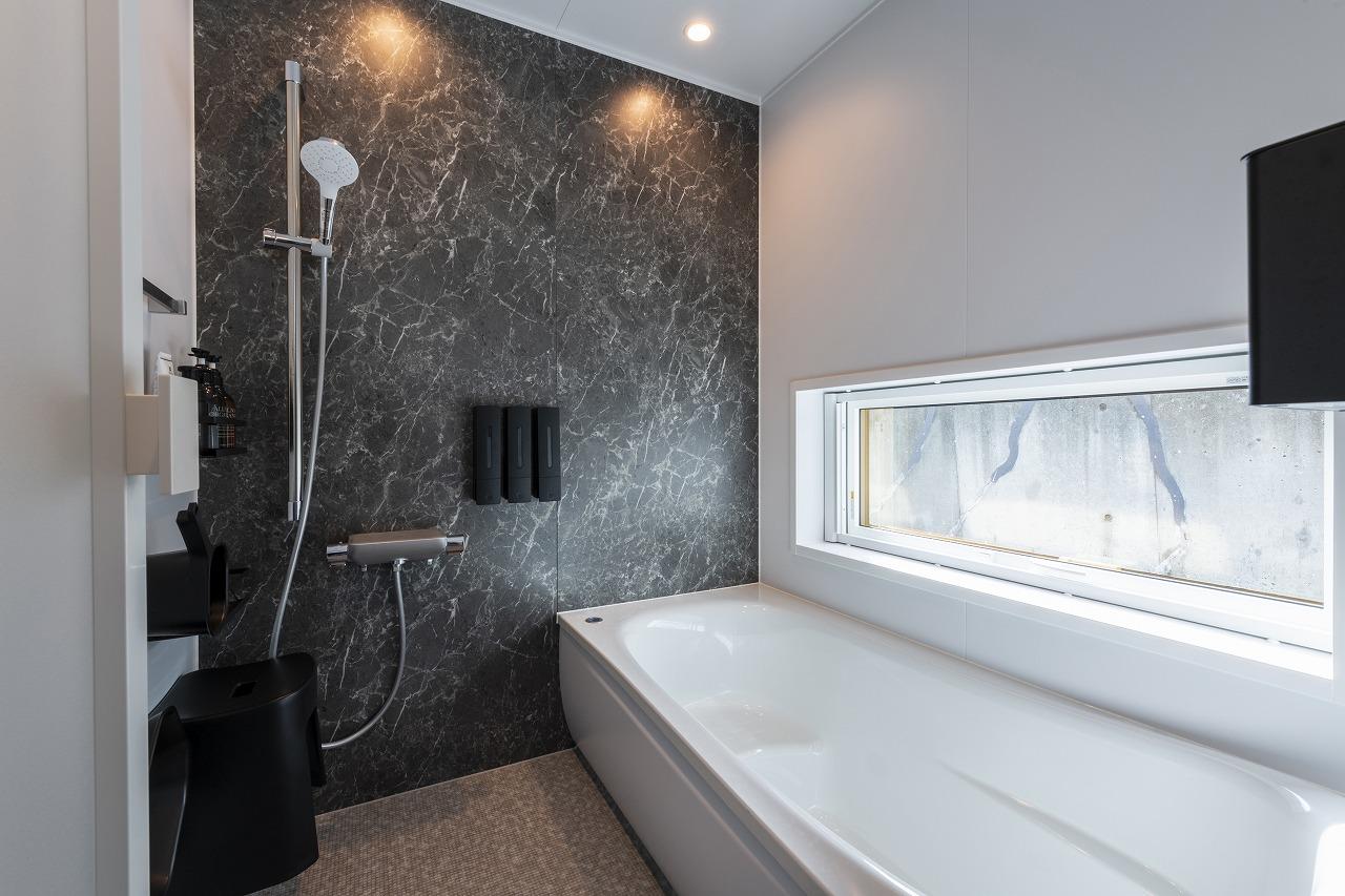 バスルーム、窓：大理石調のアクセントパネルと景色を取り込む水平窓で上質なバスタイムを