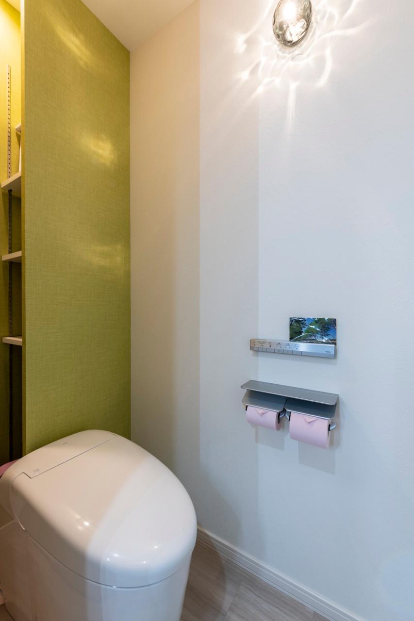 トイレ、収納、壁紙：1階トイレは背面の見えない位置に可動棚を配置、ビタミンカラーのクロスで明るい空間に