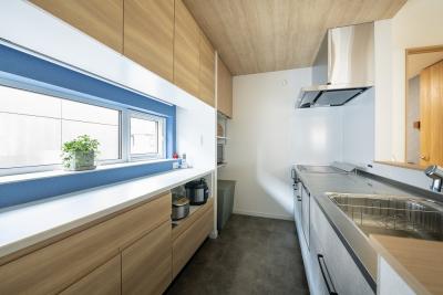 キッチン：二の字型に配置した食器棚の間に窓を設置。明るく清潔感のあるキッチンが完成